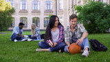Students sitting on grass near college, acquaintance, first day on campus