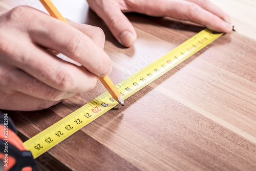 Carpenter Making A Mark With A Pencil After Measuring A Wooden Board With A Measuring Tool