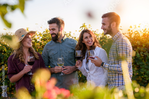 Happy friends having fun drinking wine at winery vineyard - Friendship concept with young people enjoying harvest time together photo