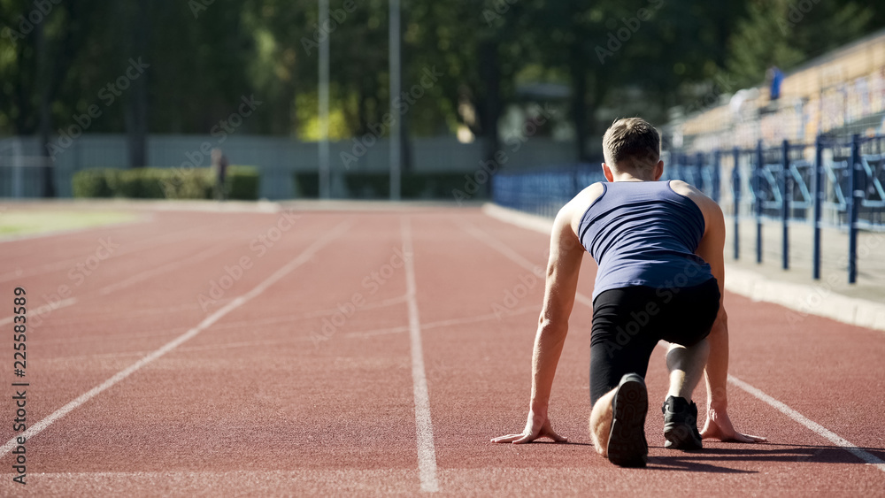 Athlete in starting position to run on stadium, professional sportsman training