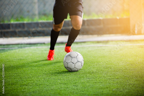 Soccer player speed run to shoot ball to goal on artificial turf.
