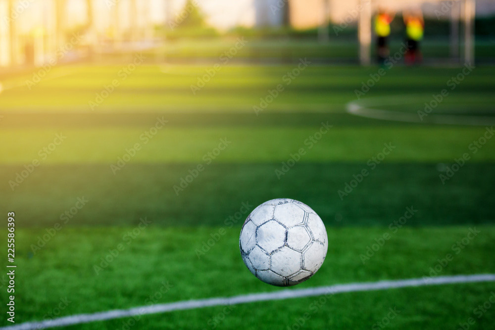 Soft focus of football bounce in front of goal line with blurry soccer player training background.