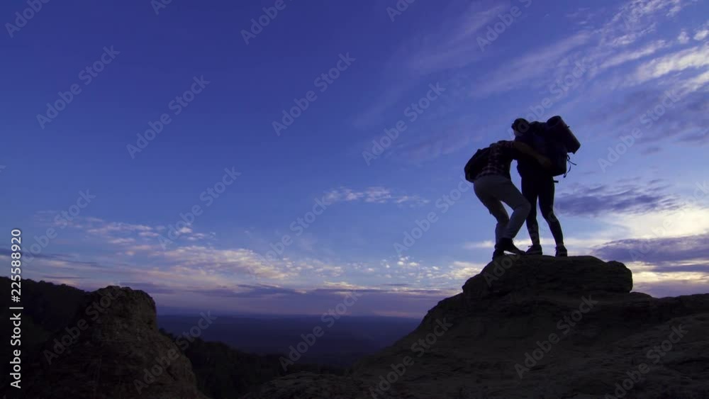 Young girl with a backpack standing on top gives a helping hand to a man Young girl with a backpack standing on top gives a helping hand to a man
