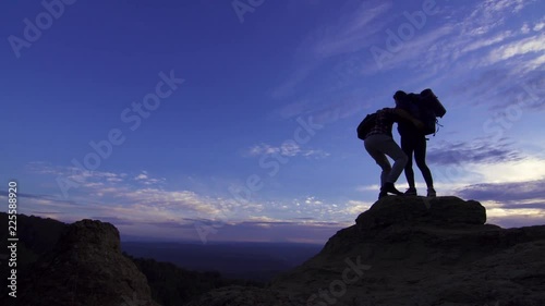 Young girl with a backpack standing on top gives a helping hand to a man