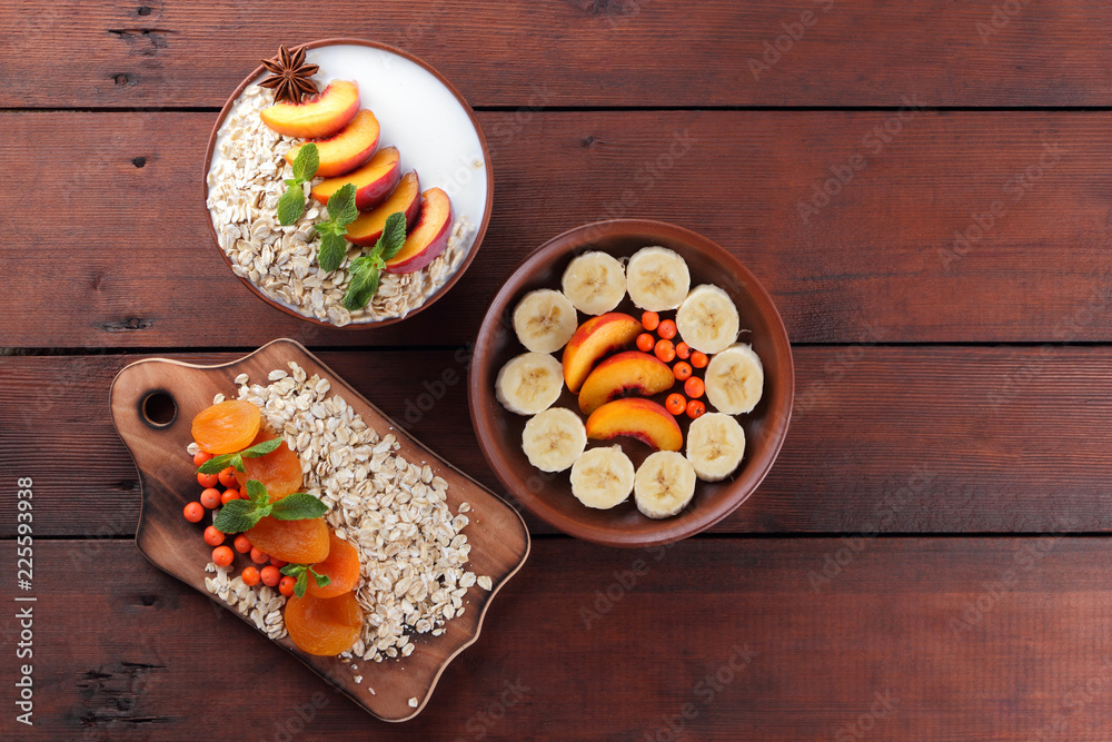 Oatmeal with fruits and green mint. Oat flakes with milk and dried apricots on wooden background. Healthy food for vegans. Dry oats with peaches, anise and berries of mountain ash Oatmeal with fruits and green mint. Oat flakes with milk and dried apricots on wooden background. Healthy food for vegans. Dry oats with peaches, anise and berries of mountain ash
