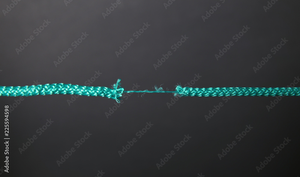 Frayed rope at breaking point on gray background