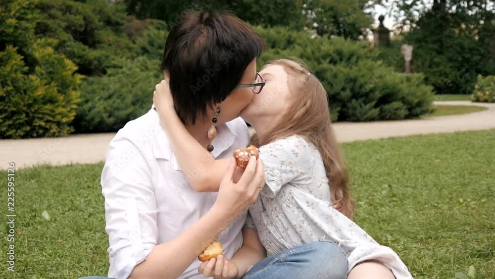 Happy Mother and Daughter gently hug and kiss sitting on a Blanket at Park Picnic Stock ビデオ | Adobe Stock