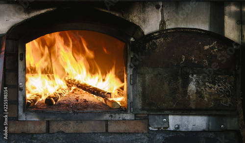 Fire roaring and burning wood in traditional masonry oven, also known as brick oven or stone oven.