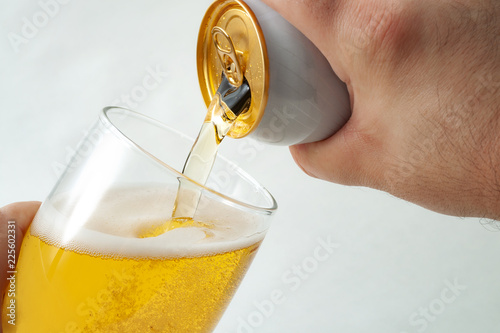 Alcoholic beverage, drinking alcohol and alcoholic content concept with close up on a hand pouring from a can of beer into a clear glass isolated on white background