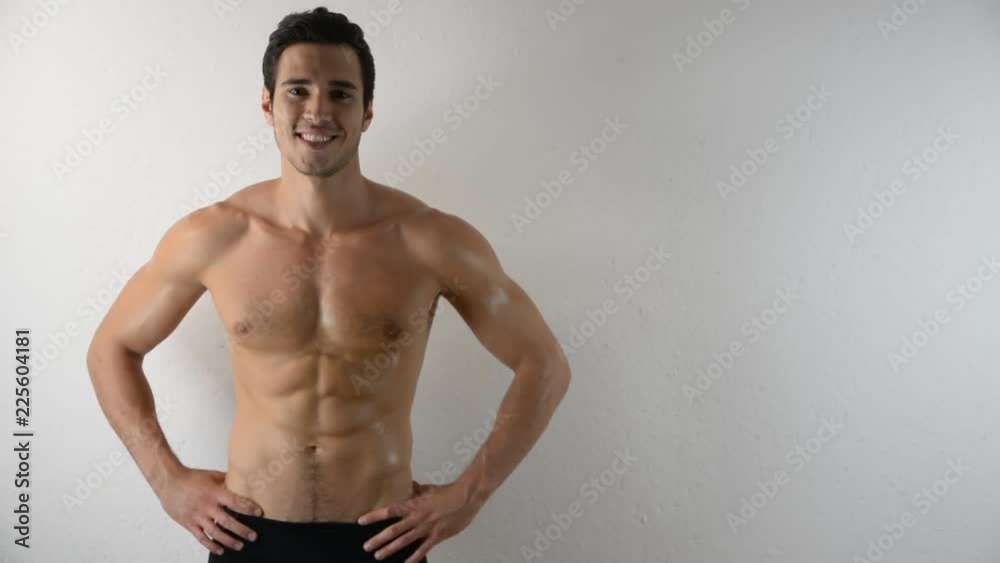 Handsome shirtless athletic young man in jeans, looking at camera in studio shot, on white background