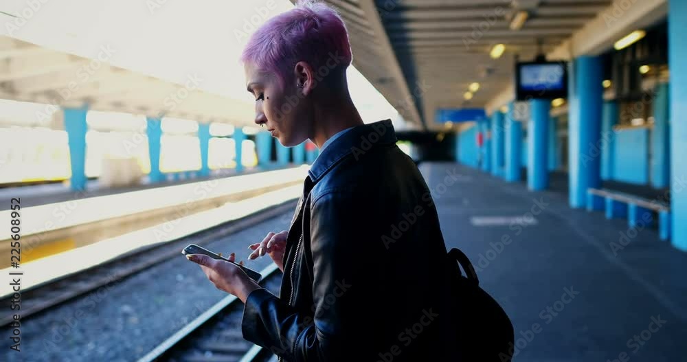 Woman using mobile phone while waiting for train 4k