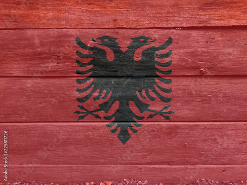 Flag of Albania on wooden wall background. Grunge Albanian flag texture, a red field with the black double-headed eagle in the center.