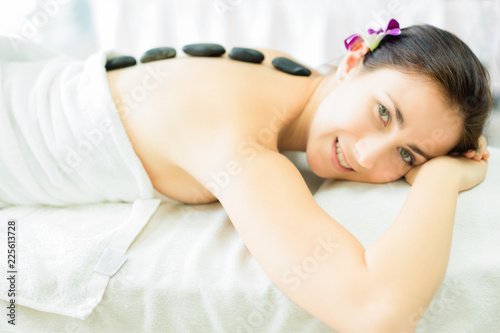 spa body treatment.beautiful woman is healing with hot stone spa in salon