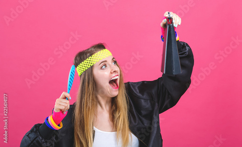 Woman in 1980's fashion playing a cowbell on a pink background photo