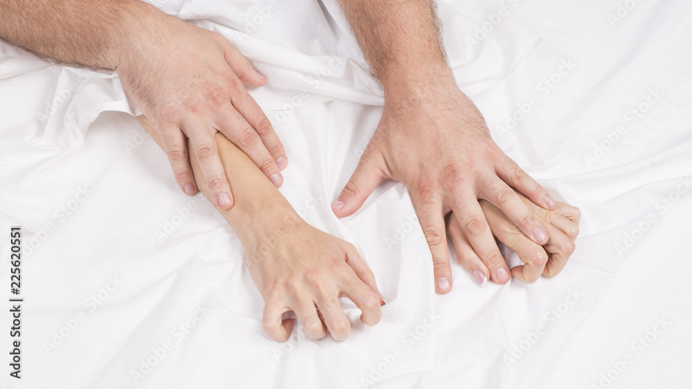 Sensual beautiful young couple is having sex on bed. Female hand