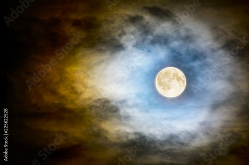 Full moon over dark cloudy sky