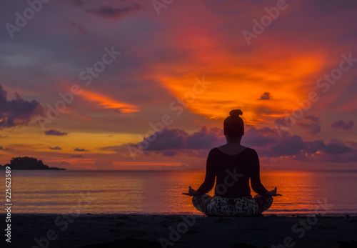Silhouette of woman sit on the beach practice yoga at sunset © Chris