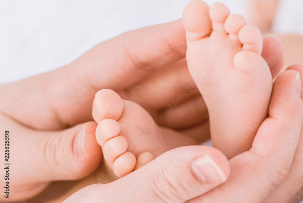 Close-up of mother hands holding tiny baby feet Close-up of mother hands holding tiny baby feet