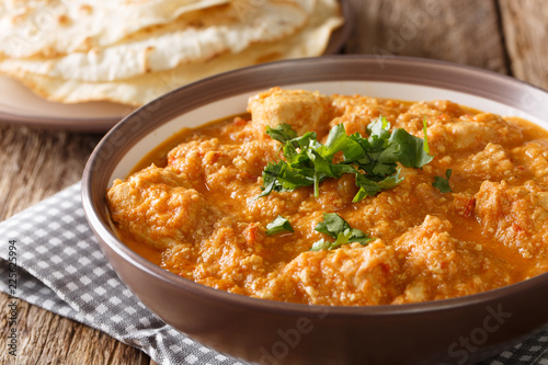 Chicken changezi cooked in a sauce with yogurt, nuts, spices, tomatoes served with flat bread close-up. horizontal