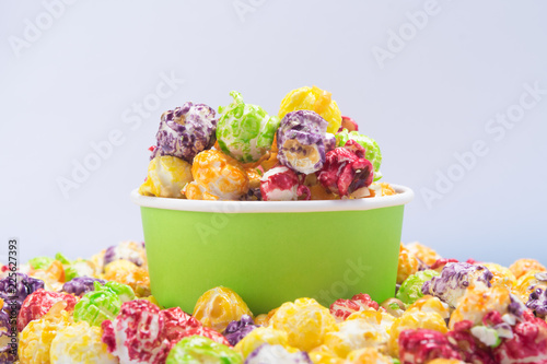 a bucket of multi-colored popcorn stands in a pile of cereal, on a white background