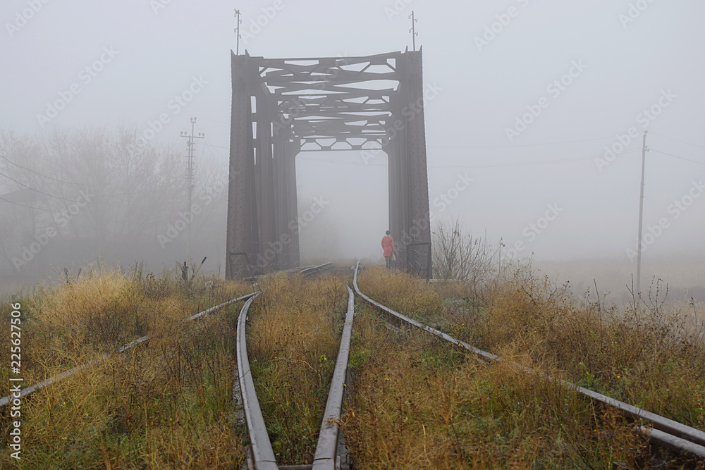 Railway bridge in the fog and a lonely passerby.