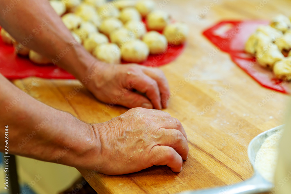 Bäcker rollt Teig zu kleinen Rosinenbrötchen Bäcker rollt Teig zu kleinen Rosinenbrötchen