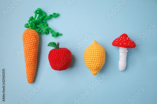 set of knitted toys lemon, carrot, apple, amanita on blue background. Earlier tactile development of children, craft toys, vegetarian menu concept photo