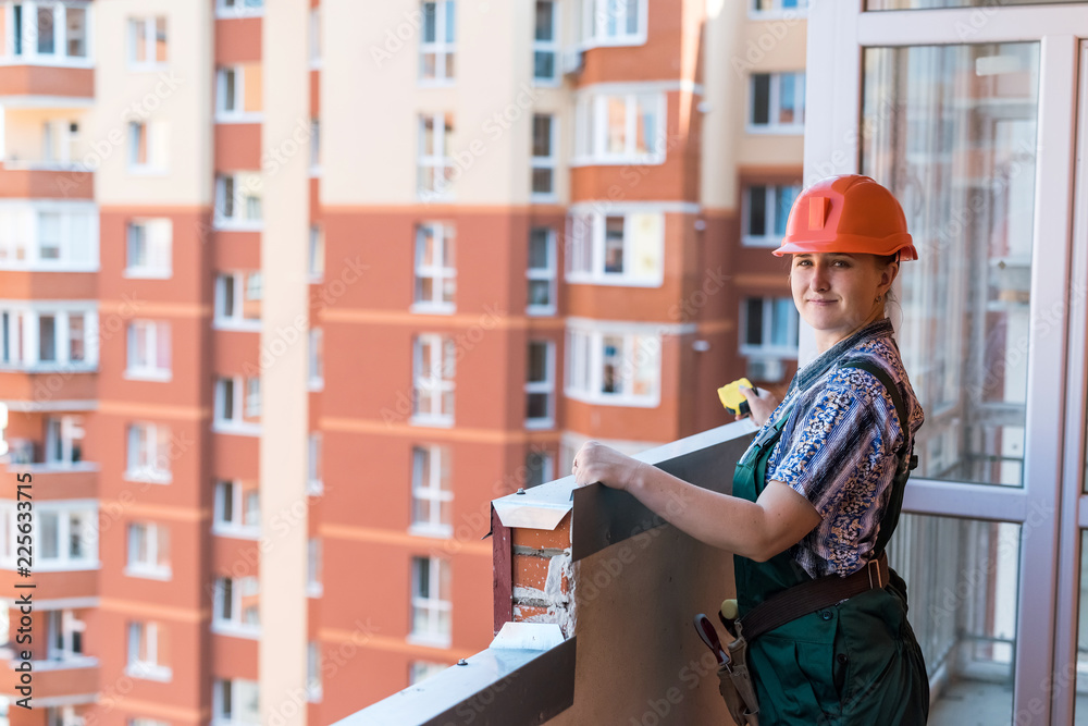 Woman builder posing on balcony in new apartment Woman builder posing on balcony in new apartment