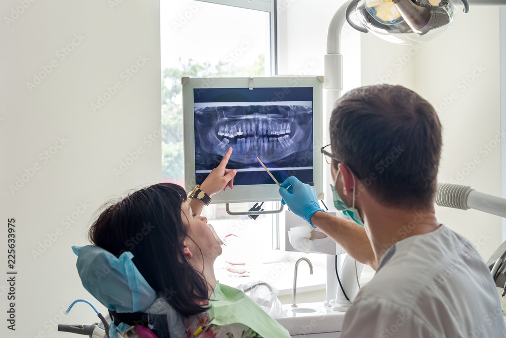 Fototapeta premium Doctor dentist pointing on patient's X-ray on monitor