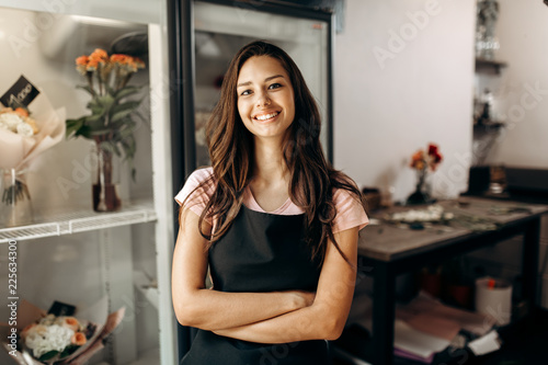 Young beautiful florist in a black apron stands and smiles in a 