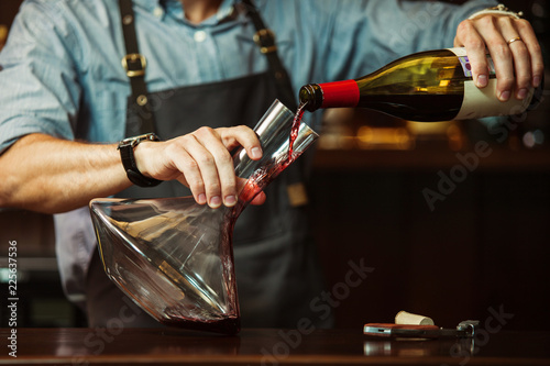 Sommelier pouring red wine into carafe to make perfect color photo