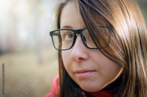 Face portrait of dreaming caucasian woman with long brown hair in eyeglasses.