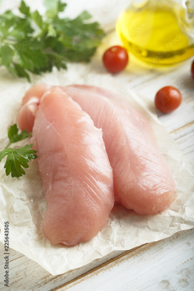 Chicken fillet, uncooked on the rustic desk with other ingredients Chicken fillet, uncooked on the rustic desk with other ingredients