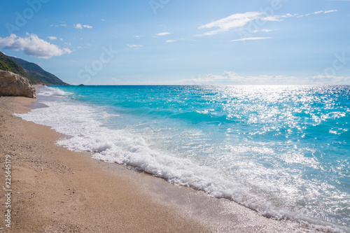 Blue ocean shore with golden sands and rocks