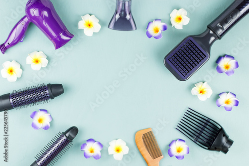 Hairdressing tools with flowers on blue wooden background