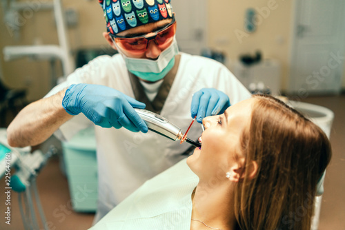 Dentist carries out treatment of the young girl with braces in dental office.