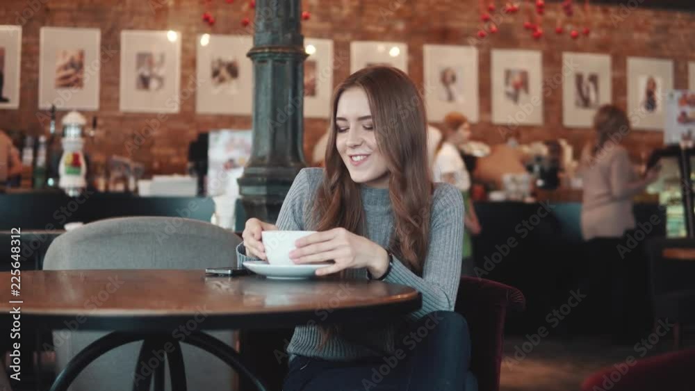 portrait of a pretty girl in a cafe. girl makes selfie on camera smartphone and drinks coffee portrait of a pretty girl in a cafe. girl makes selfie on camera smartphone and drinks coffee