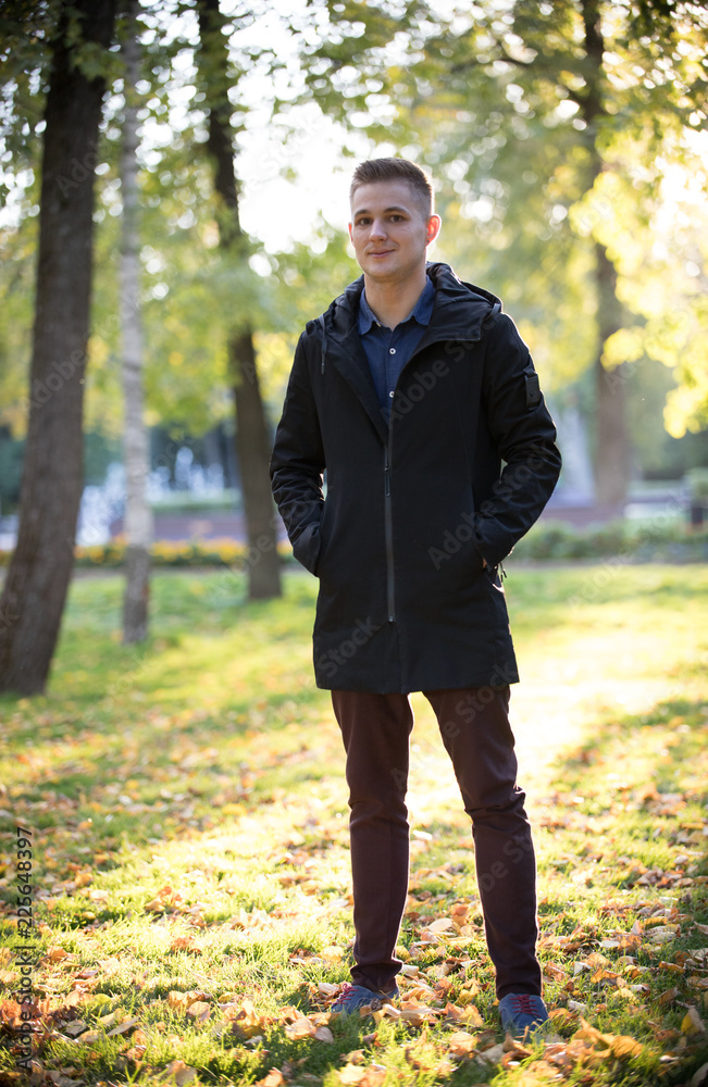 Handsome and young man in a black jacket standing in the park Handsome and young man in a black jacket standing in the park