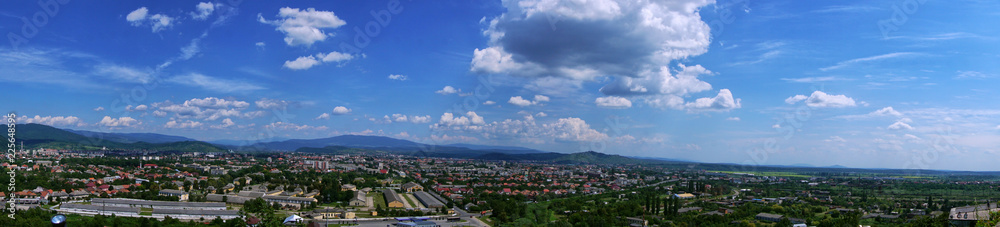 Beautiful panorama of the city with mountains. There are buildings, houses with nature. Blue sky with beautiful clouds.