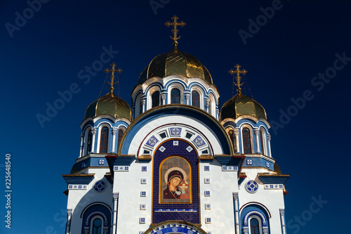 Brick white orthodox church with golden baths against a blue sky in summer on a sunny day on Kemerovo city
