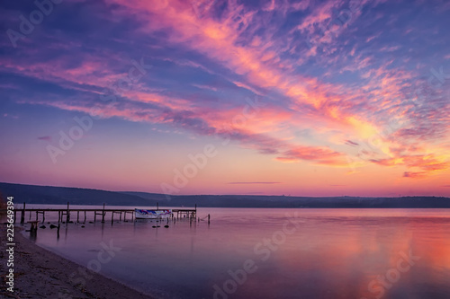 beautiful and calm sunset sunrise on a lake with pier and boat.