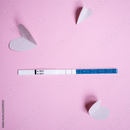 Positive pregnancy test with two strips and pink hearts. pink background, copy space photo