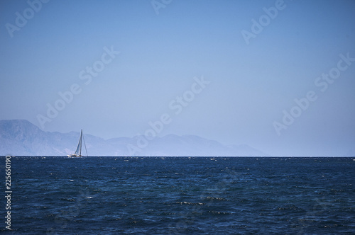 Sailing yacht on the horizon in the Aegean Sea. Seascape overlooking the island.