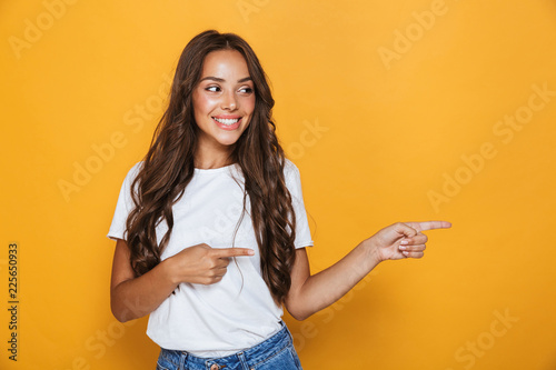 Young pretty woman posing isolated over yellow background showing copyspace.