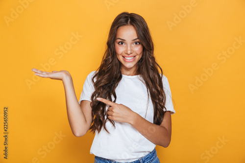 Young pretty woman posing isolated over yellow background showing copyspace.