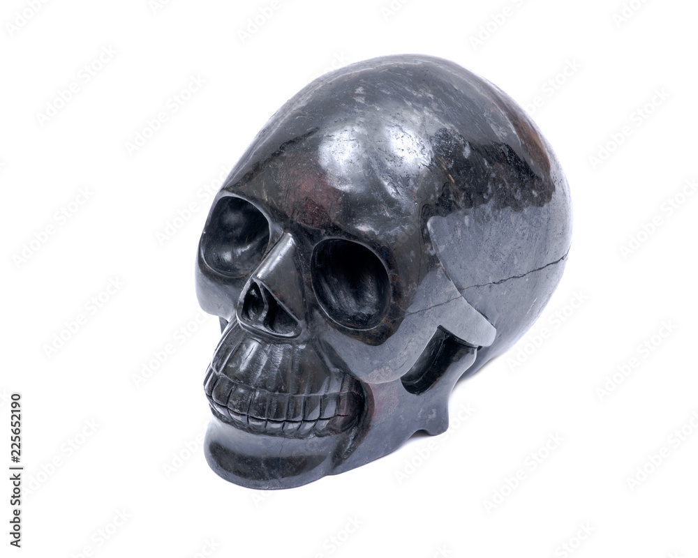 Black realistic carved stone skull with Astrophyllite blades from Russia, isolated on white background. Black realistic carved stone skull with Astrophyllite blades from Russia, isolated on white background.