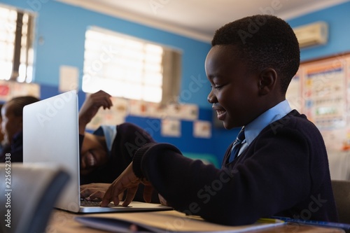 Smiling student using laptop in classroom photo