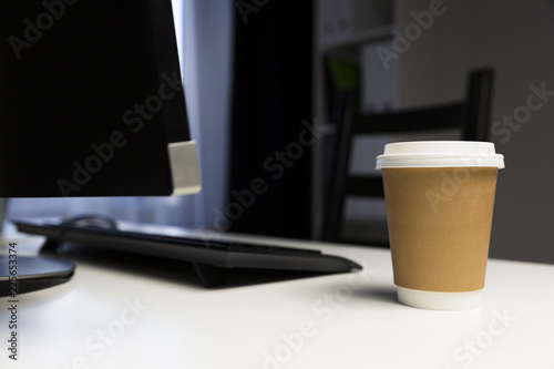 Cup of coffee in office next to computter. Working late concept photo
