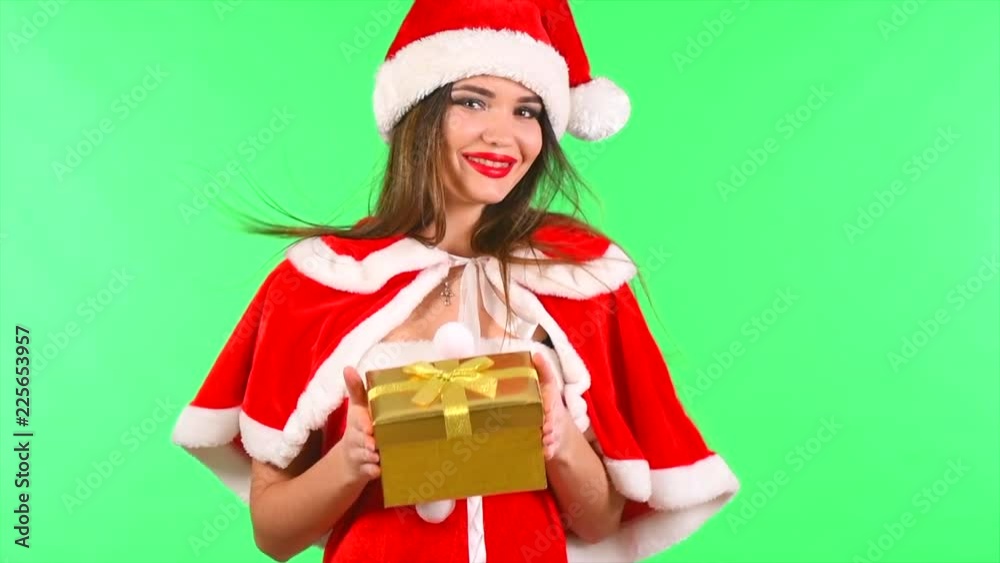 Christmas scene. Sexy Santa with gift box. Brunette young woman in party costume holding gift box over green screen background. Slow motion 4K UHD video 3840X2160 Christmas scene. Sexy Santa with gift box. Brunette young woman in party costume holding gift box over green screen background. Slow motion 4K UHD video 3840X2160