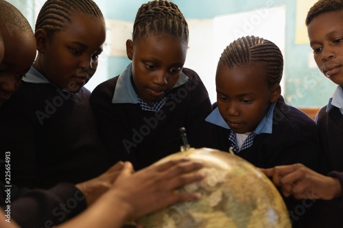 Schoolkids using globe in classroom
